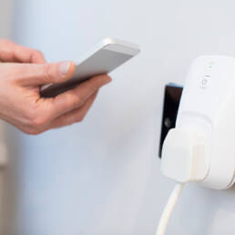 A smart phone being held up to a smart plug at home