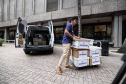 An employee loading boxes of Oceanit Assure tests into a van outside Oceanit headquarters