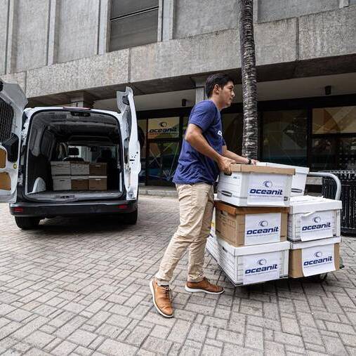 An employee loading boxes of Oceanit Assure tests into a van outside Oceanit headquarters