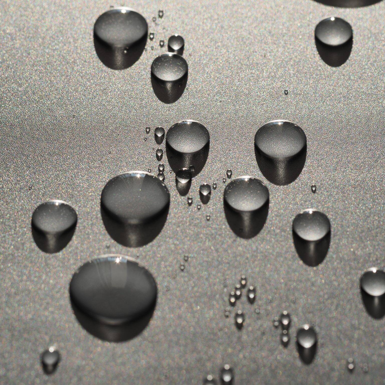 Water droplets beading up on a gray metal background