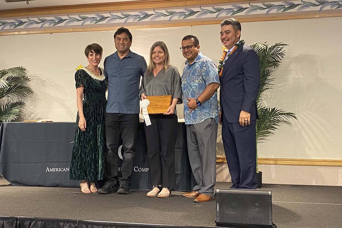 A group of three Oceanit employees standing on stage accepting a plaque