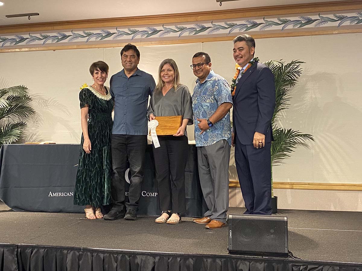 A group of three Oceanit employees standing on stage accepting a plaque